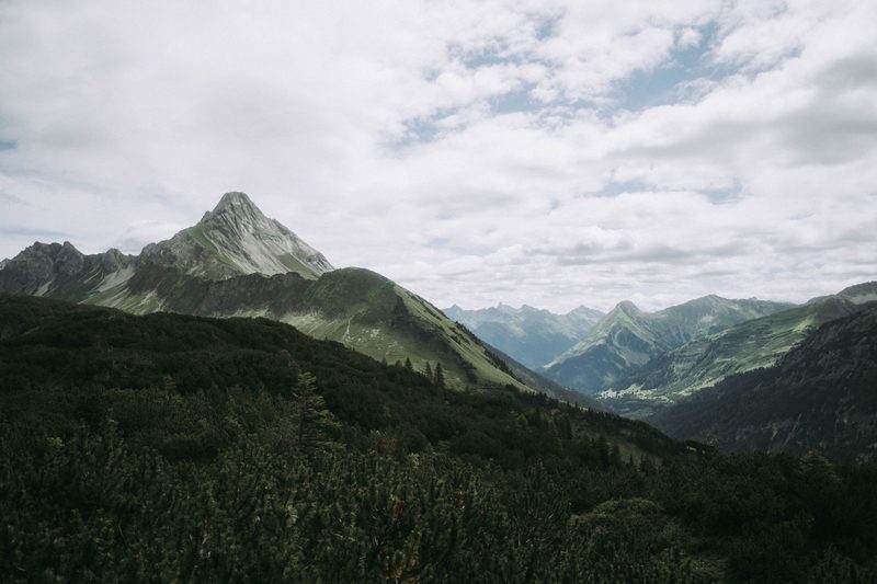 Alpenpanorama im Rappenalptal — spitzer Gipfel über bewaldeten Hängen, dahinter die hohen Allgäuer Berge