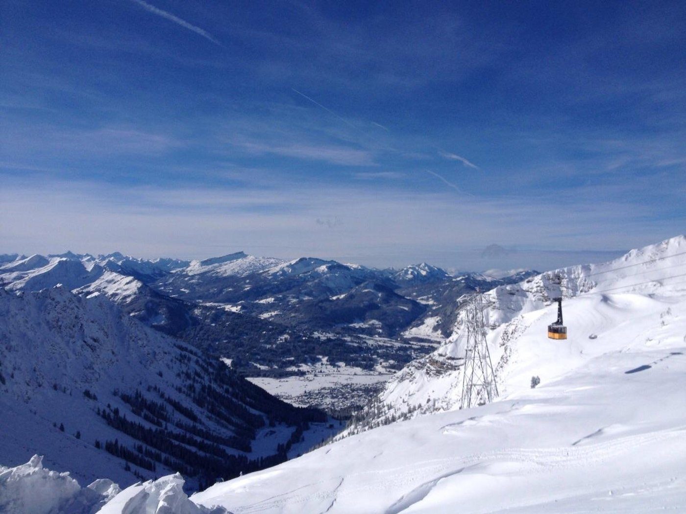Yellow cable car gondola over a snow-covered Allgäu valley, snow-capped mountain ridges in the background