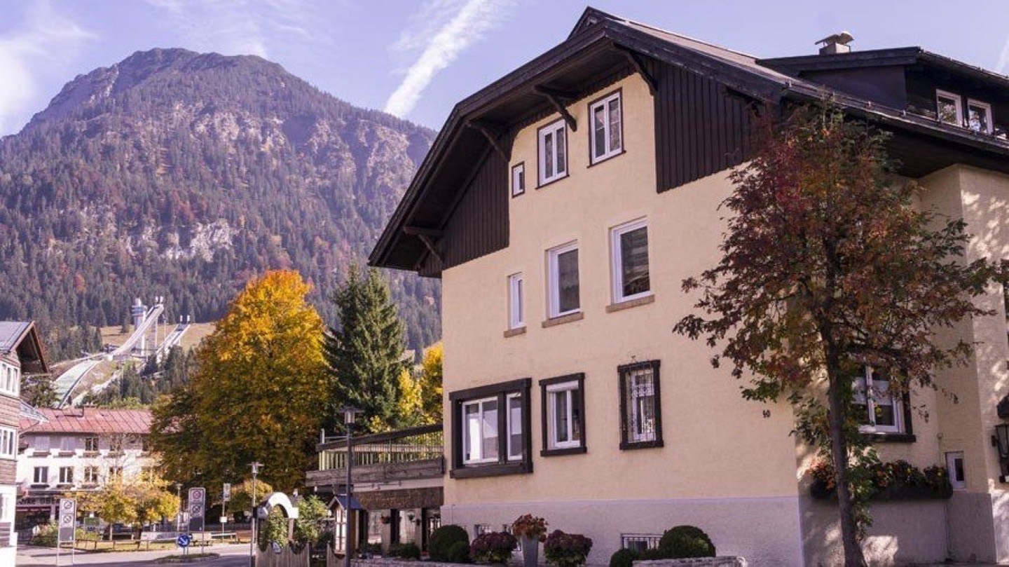 Haus NH40 an der Nebelhornstraße 40 in Oberstdorf, mit Schattenberg-Schanze und Hauptkamm im Hintergrund.