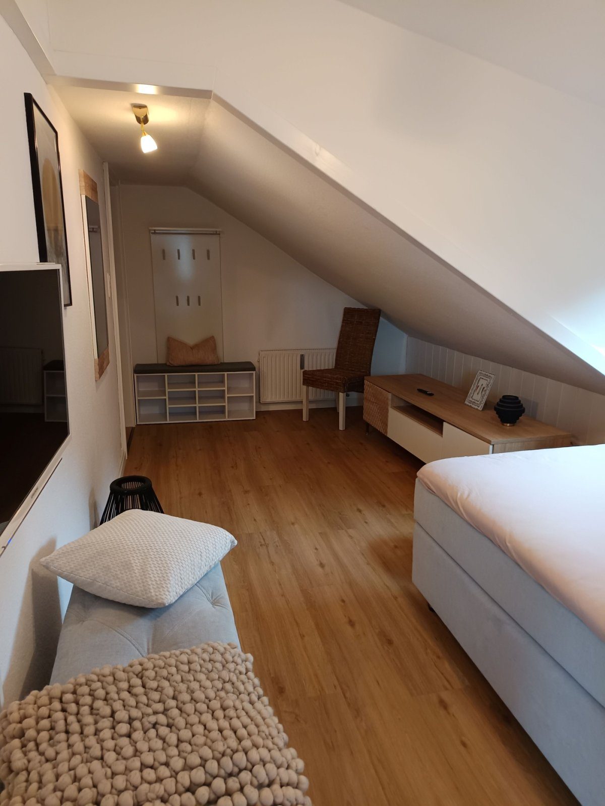 Studio unter der Dachschräge mit Bett, Sitzbank und Garderobe.