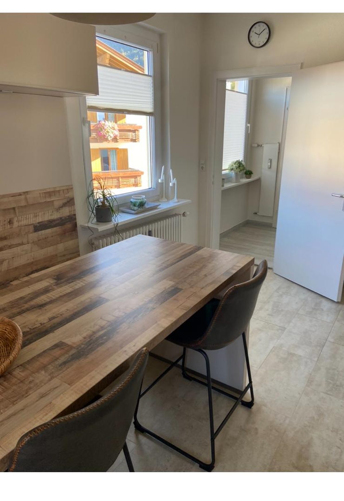 Küche mit langem Holztisch, zwei Lederstühlen und Fenster zum Nachbarhaus.